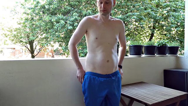 Man undressing outside on the balcony naked, he jerks his semi-erect shaved cock which stands erect and gets dressed again