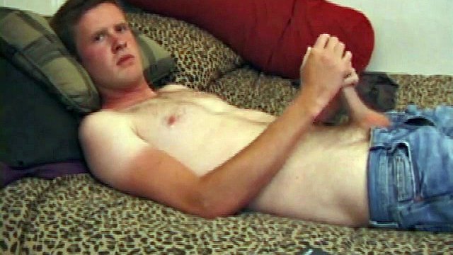 Nate Richie is tanned like a guy who works outside all day. He pulls his shirt off and pulls his pants down to his knees.