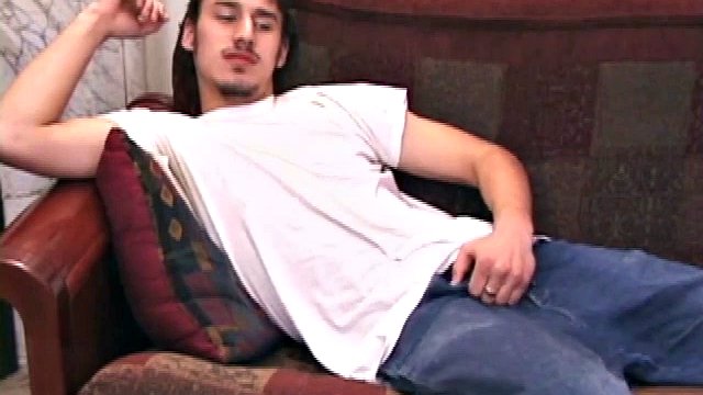 On a couch, young Ricky Underton rubs himself through baggy jeans and a t-shirt. Unbuckling and flaunting a hairy trail, he pulls his t-shirt off and pulls his jeans down, just enough for a big dick head to get out.